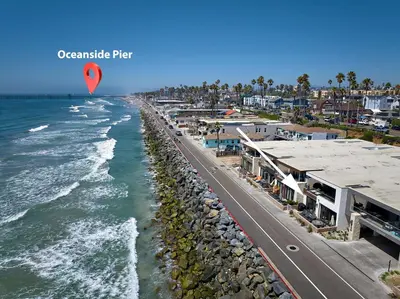 a kite flying over a beach next to the ocean at Water Front Spectacular Ocean View Large Balcony AC Pet Friendly in Oceanside