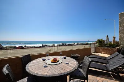 a table on a balcony with a view of the beach at Water Front Spectacular Ocean View Large Balcony AC Pet Friendly in Oceanside