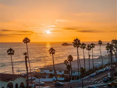 a sunset over a city with palm trees and the ocean at 15 Feet to the Water in Oceanside