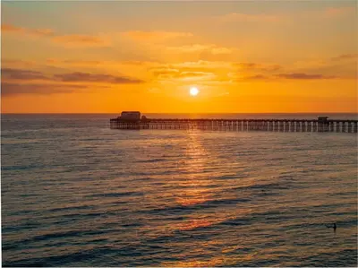 a pier in the ocean with the sunset in the background at 15 Feet to the Water in Oceanside