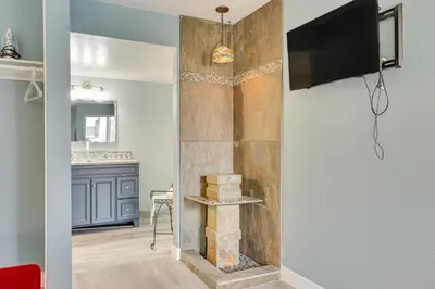a living room with a stone fireplace with a flat screen tv at Carlsbad Rental with Private Balcony and Pool Access! in Carlsbad