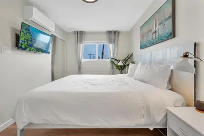 a white bedroom with a large bed and a window at Ultimate Oceanside Retreat | Tower 9 Across from the Beach in Oceanside