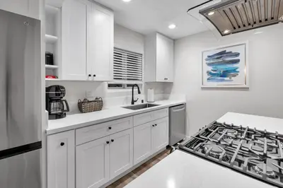 a kitchen with white cabinets and a stove at Ultimate Oceanside Retreat | Tower 9 Across from the Beach in Oceanside