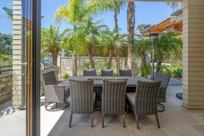 a patio with a table and chairs and palm trees at Ocean View Del Mar Beach Home w Jacuzzi in San Diego