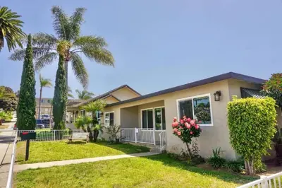 a house with palm trees and a sidewalk at Spacious Beach House! Walk to Beach and Pier in Oceanside