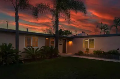 a house with a palm tree in front of a sunset at Relax and Play Pool, Hot Tub and Sleeps 16 in San Diego