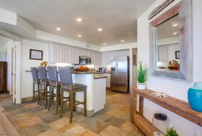 a kitchen with bar stools and a stainless steel refrigerator at Aloha Breeze 1 in San Diego