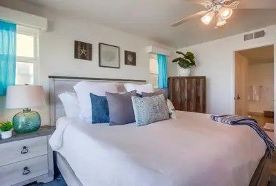 a bedroom with a large white bed with blue pillows at Aloha Breeze 1 in San Diego