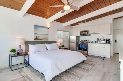 a bedroom with a large white bed and a kitchen at Bayside 4 in San Diego