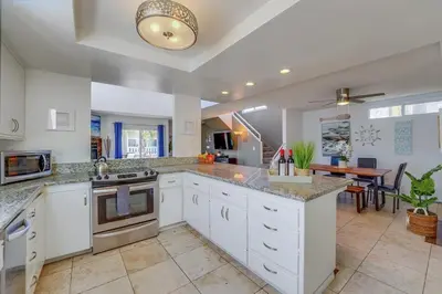 a large kitchen with white cabinets and a table at Beach Haven 2 in San Diego