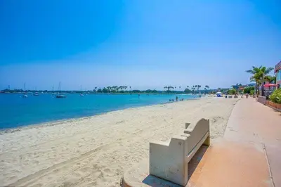 a bench sitting on a beach next to the water at Beach Haven 2 in San Diego