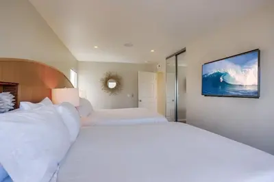 a bedroom with a large white bed with a painting on the wall at Beachside 2 in San Diego
