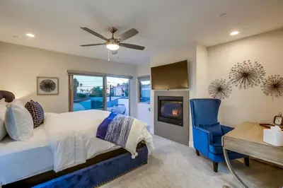 a bedroom with a bed and a desk and a fireplace at CA Dreaming in San Diego