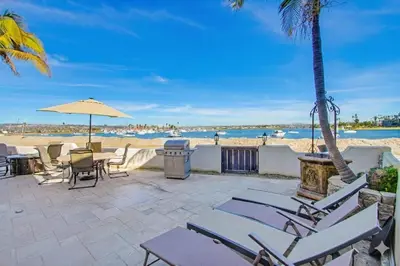 a patio with chairs and an umbrella and the beach at Point Break 1 in San Diego