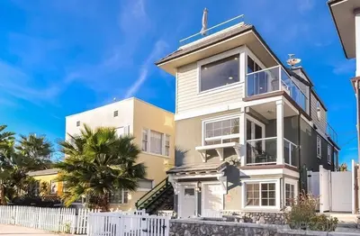 a white and yellow house with a white fence at Bay View in San Diego