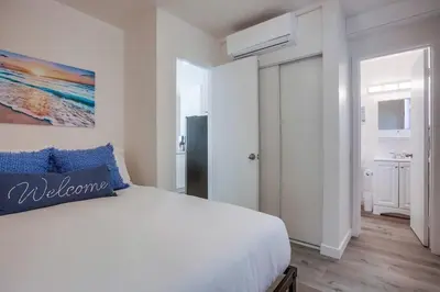 a white bedroom with a bed and a painting on the wall at Strandway Suite 3 in San Diego