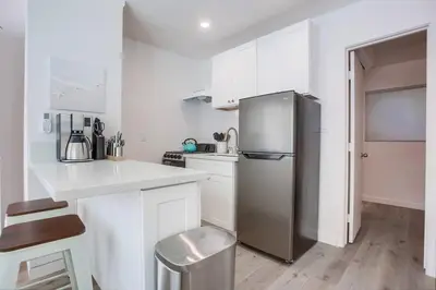 a kitchen with a stainless steel refrigerator and white cabinets at Strandway Suite 3 in San Diego