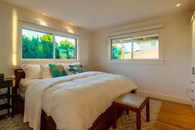 a bedroom with a large bed with two windows at Sunset Beach in Encinitas