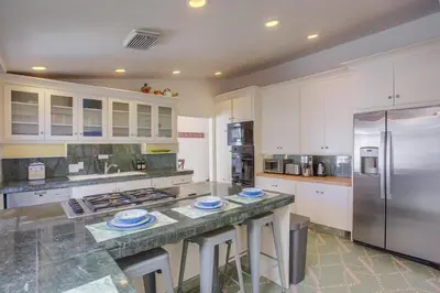 a kitchen with white cabinets and a stainless steel refrigerator at Treasure Villa in San Diego