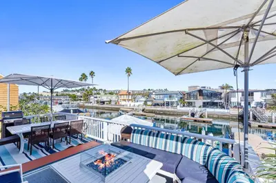 an outdoor deck with a swimming pool and an umbrella at Stunning BayVIEW Home with Epic Waterfront Views! in Newport Beach