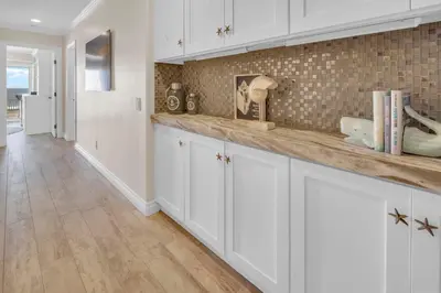 a kitchen with white cabinets and a tile wall at Seaview 1135A in Oceanside