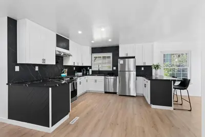 a kitchen with white cabinets and black counter tops at Safari Vines Retreat in Escondido