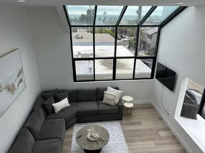 a living room with a couch and some windows at La Jolla Townhouse steps away from Windansea beach in San Diego