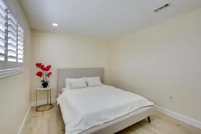 a white bedroom with a bed and a vase with red flowers at Centrally Located Retreat 5 Mi to San Diego Zoo! in San Diego