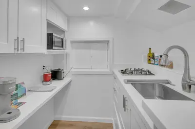 a white kitchen with white cabinets and a sink at Near All Things SD - Canyonview - Jacuzzi - EV Charge in San Diego
