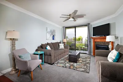 a living room with a couch and chairs and a tv at Oceanside Beach Condos in Oceanside