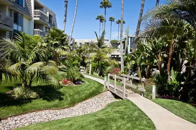 a garden with a white fence and palm trees at Oceanside Beach Condos in Oceanside