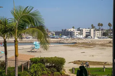 a beach with a palm tree and a beach with buildings at Oceanside Beach Condos in Oceanside