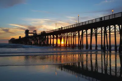 a pier at the beach with the sun setting at Oceanside Beach Condos in Oceanside