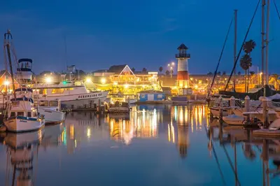 a marina with boats and a lighthouse at night at Oceanside Beach Condos in Oceanside