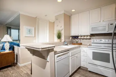 a kitchen with white cabinets and white appliances at Oceanside Beach Condos in Oceanside