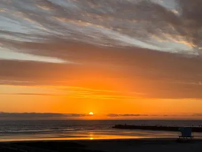 a sunset over the ocean with a bench on the beach at Oceanside Beach Condos in Oceanside