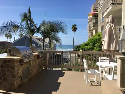 a patio with a grill and a table and chairs and the ocean at Oceanside Beach Condos in Oceanside