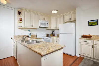 a kitchen with white cabinets and a white refrigerator at Oceanside Beach Condos in Oceanside
