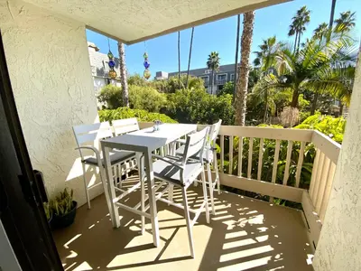 a white table and chairs on a balcony with palm trees at Oceanside Beach Condos in Oceanside