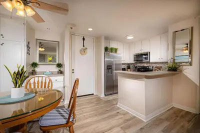 a kitchen with white cabinets and a table and chairs at Oceanside Beach Condos in Oceanside