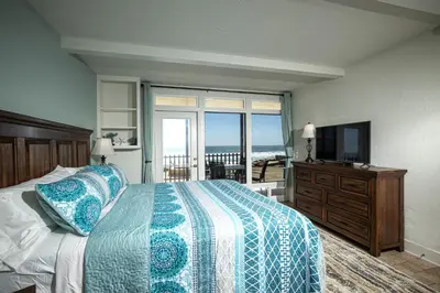 a bedroom with a bed and a television and a balcony at Beachfront Retreat in Oceanside