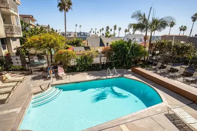 a large swimming pool with chairs and palm trees at Oceanside Beach Condos in Oceanside