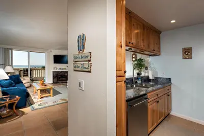 a kitchen with a refrigerator and a living room at Oceanside Beach Condos in Oceanside