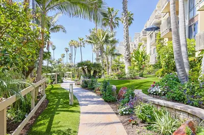 a walkway in front of a building with palm trees at Oceanside Beach Condos in Oceanside