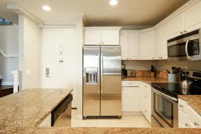 a stainless steel refrigerator in a kitchen with white cabinets at Oceanside Beach Condos in Oceanside