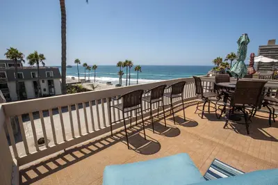 a balcony with chairs and a table and the beach at Oceanside Beach Condos in Oceanside
