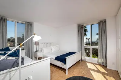 a white bedroom with a bed and a window at Oceanside Beach Condos in Oceanside