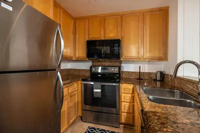 a kitchen with wooden cabinets and a stainless steel refrigerator at Oceanside Beach Condos in Oceanside