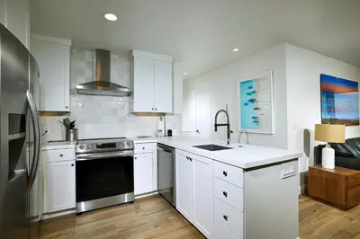 a kitchen with white cabinets and a black appliance at Oceanside Beach Condos in Oceanside