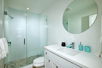 a white bathroom with a sink and a mirror at Oceanside Beach Condos in Oceanside